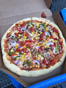 Domino's pizza topped with vegan cheese and lots of sweetcorn, tomato cubes, green and red pepper, red onion, and mushrooms.