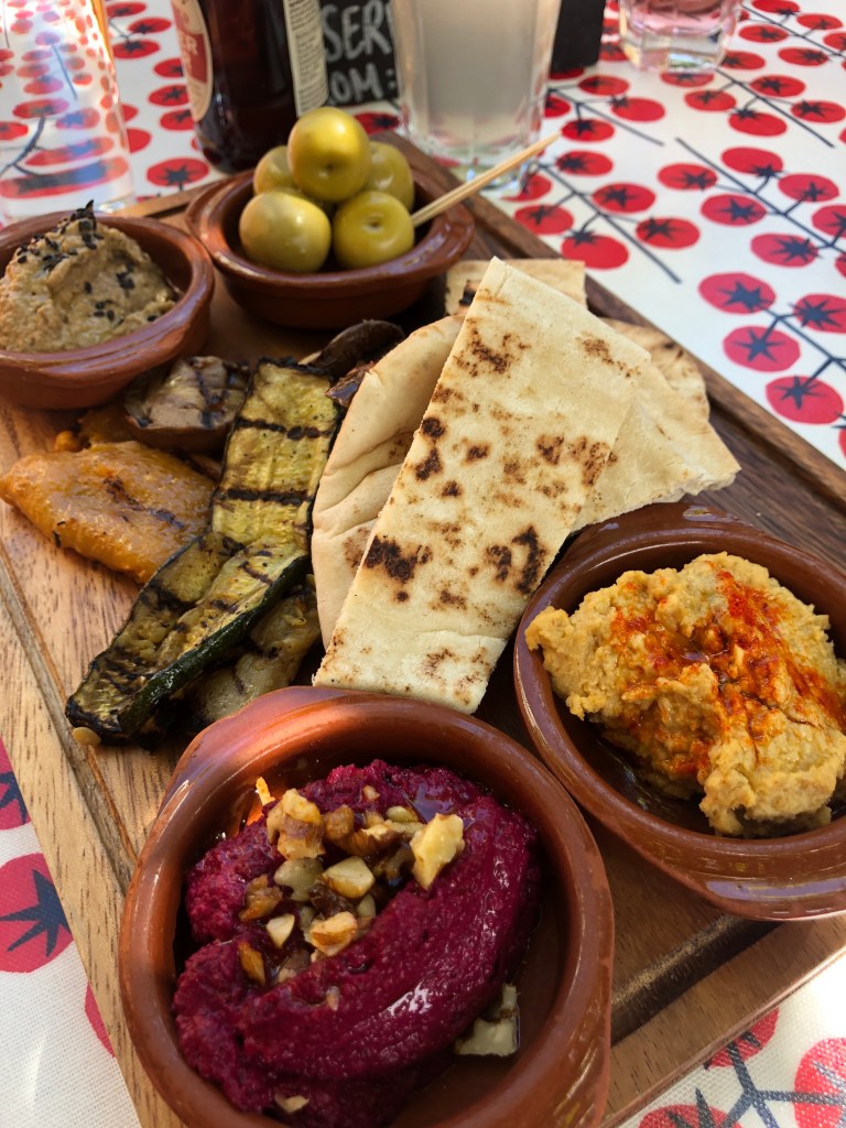 Vegan mezze board from The Punter pub in Oxford featuring beetroot houmous, classic houmous, baba ganoush, olives, grilled vegetables and pita bread.