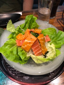 ice bowl with iceberg lettuce leaves in, topped with three different types of seaweed and vegan mock salmon