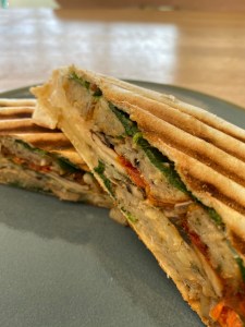 toasted wrap cut in half, seen from side on. Sausage, spinach and tomato filling is visible.