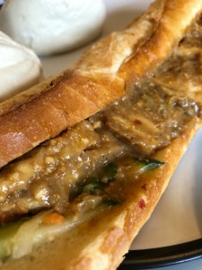 crusty white baguette sliced in half with tofu slices drenched in peanut sauce