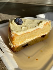 slice of sponge cake, two layers with buttercream in between and on top. two blueberries inside the cake and one on top for decoration.
