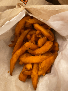 paper bag ripped open to reveal thin cut sweet potato fries.