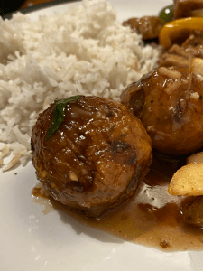 Small vegetable balls on a plate coated in gravy with white rice in the background, from the First Floor restaurant in Oxford