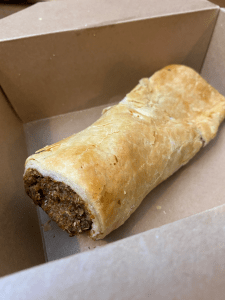 open cardboard box with 6 inch sausage roll, some filling visible from the end.