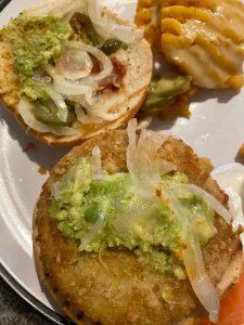 inside of burger - breaded chicken style patty with small spoonful of smashed avocado and white onions on top.