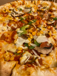 close up of pizza toppings - slice mushroom, sweetcorn, green peppers, mock meat