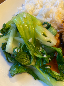 Pile of wilted green vegetables with boiled rice