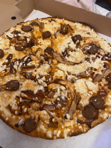 pizza in pizza box with vegan meatballs, vegan chicken strips and copious amounts of cheese